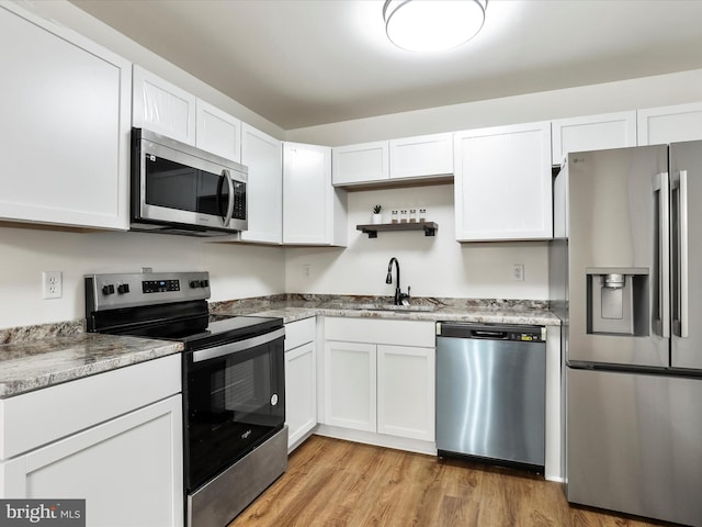 kitchen with open shelves, white cabinetry, stainless steel appliances, and a sink