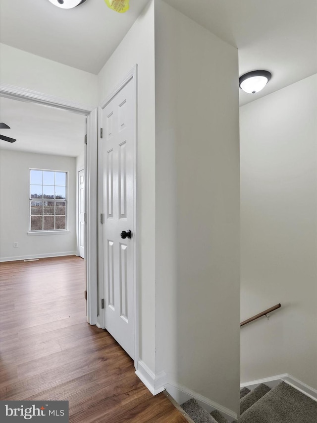 hallway featuring dark wood-style flooring, stairway, and baseboards