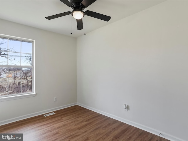 spare room with visible vents, baseboards, and wood finished floors