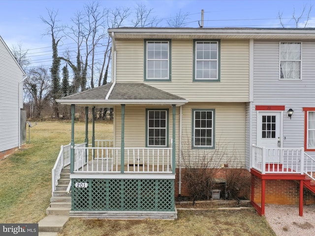 view of front of house with a shingled roof, a porch, and a front yard