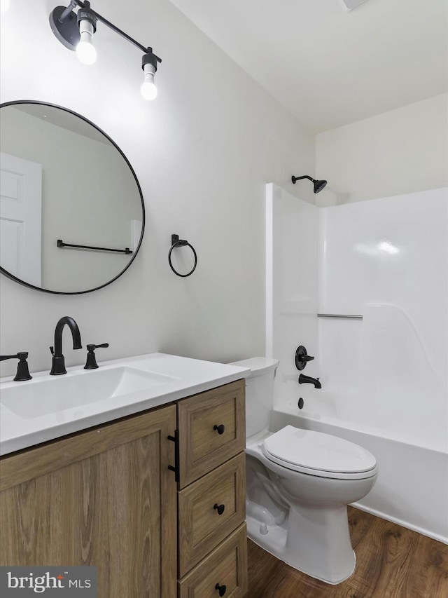 full bath featuring shower / bathtub combination, toilet, wood finished floors, and vanity