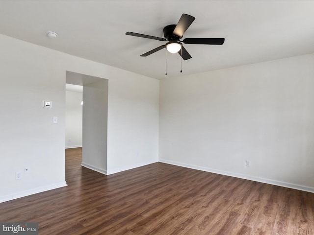 spare room featuring ceiling fan, dark wood-style flooring, and baseboards