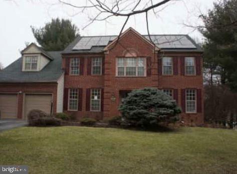 colonial house with a front lawn, solar panels, and a garage