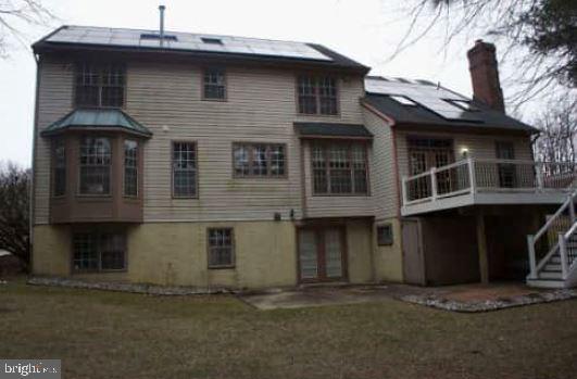 rear view of house with a lawn, solar panels, and a patio