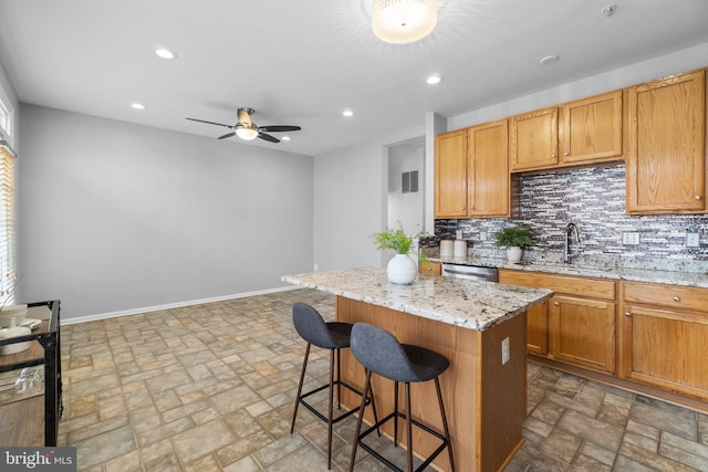 kitchen with tasteful backsplash, a kitchen island, baseboards, and a sink