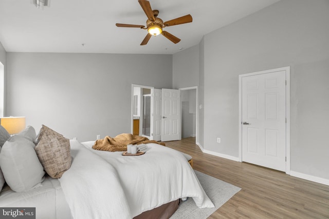 bedroom with connected bathroom, wood finished floors, visible vents, a ceiling fan, and baseboards