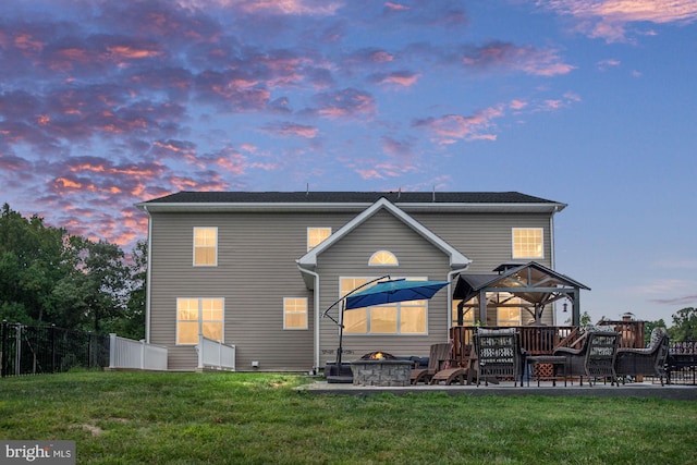 back house at dusk featuring a lawn, a gazebo, and an outdoor fire pit