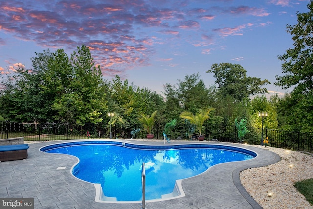 pool at dusk featuring a patio area