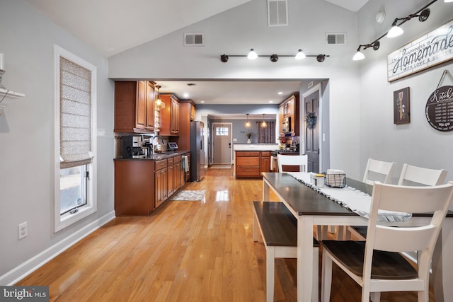 dining space with visible vents, vaulted ceiling, and light wood-style flooring