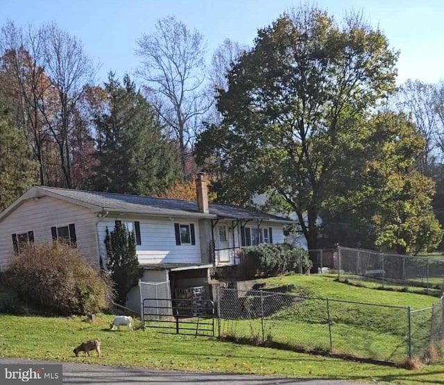 rear view of property with a fenced front yard, a chimney, and a yard