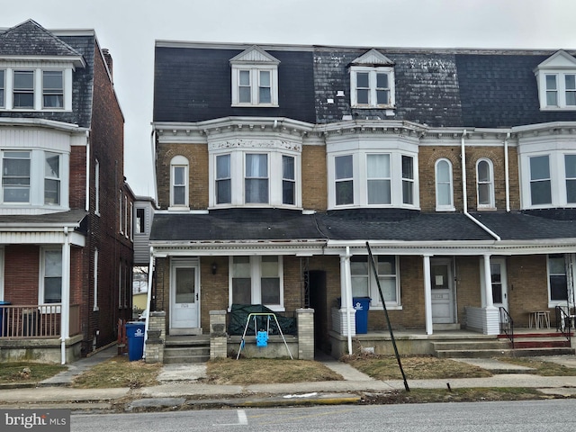 townhome / multi-family property featuring mansard roof, a shingled roof, and brick siding