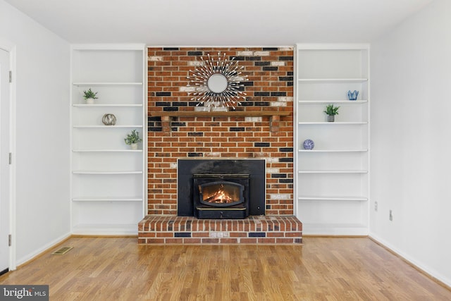 unfurnished living room featuring hardwood / wood-style floors and built in shelves