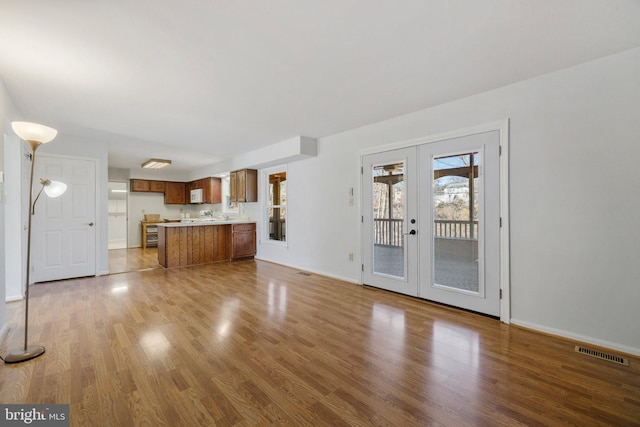 unfurnished living room with light wood-type flooring and french doors