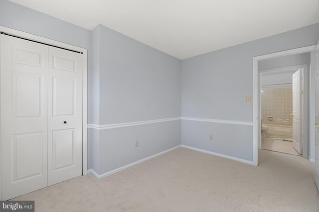 unfurnished bedroom featuring light carpet and a closet