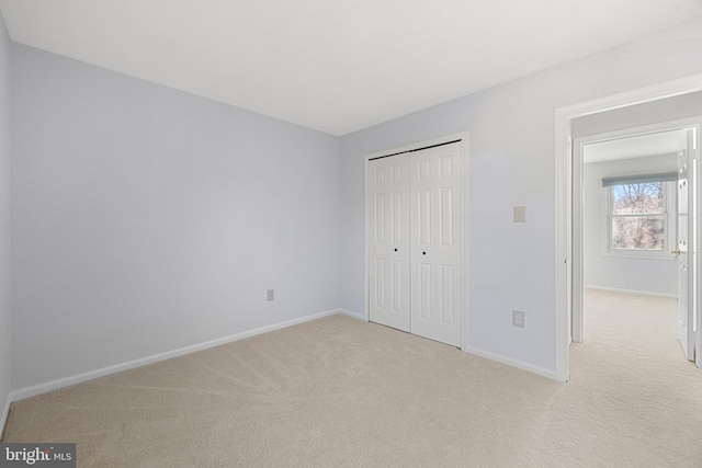 unfurnished bedroom with light carpet and a closet