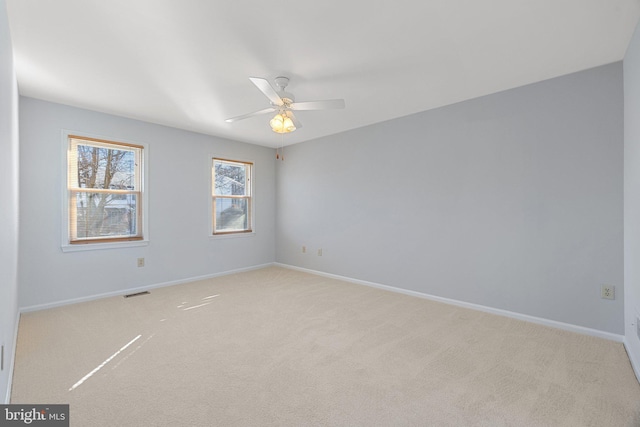 spare room featuring light colored carpet and ceiling fan