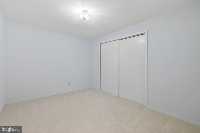 unfurnished bedroom with light carpet and a closet