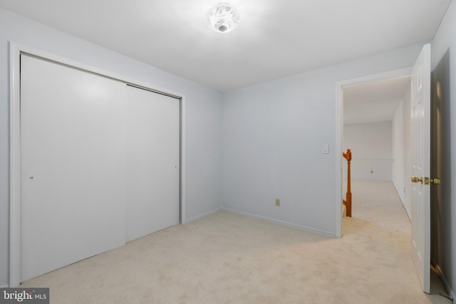 unfurnished bedroom featuring light carpet and a closet