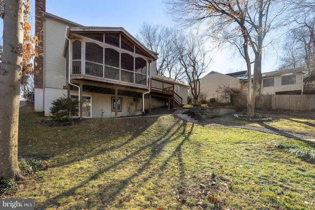 rear view of property featuring a lawn, a deck, and a sunroom