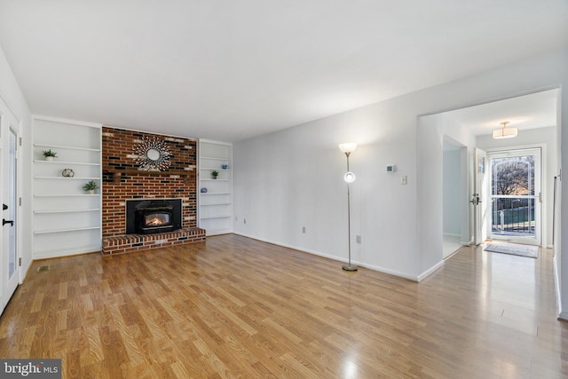 unfurnished living room featuring light wood-type flooring, a fireplace, and built in features