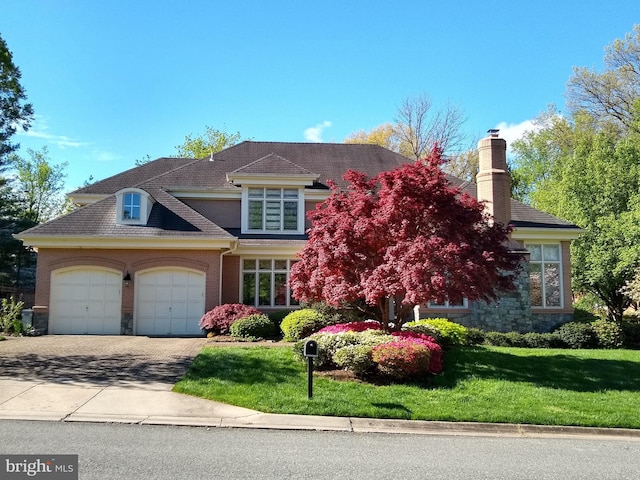 view of front facade featuring an attached garage, stone siding, a front lawn, and concrete driveway