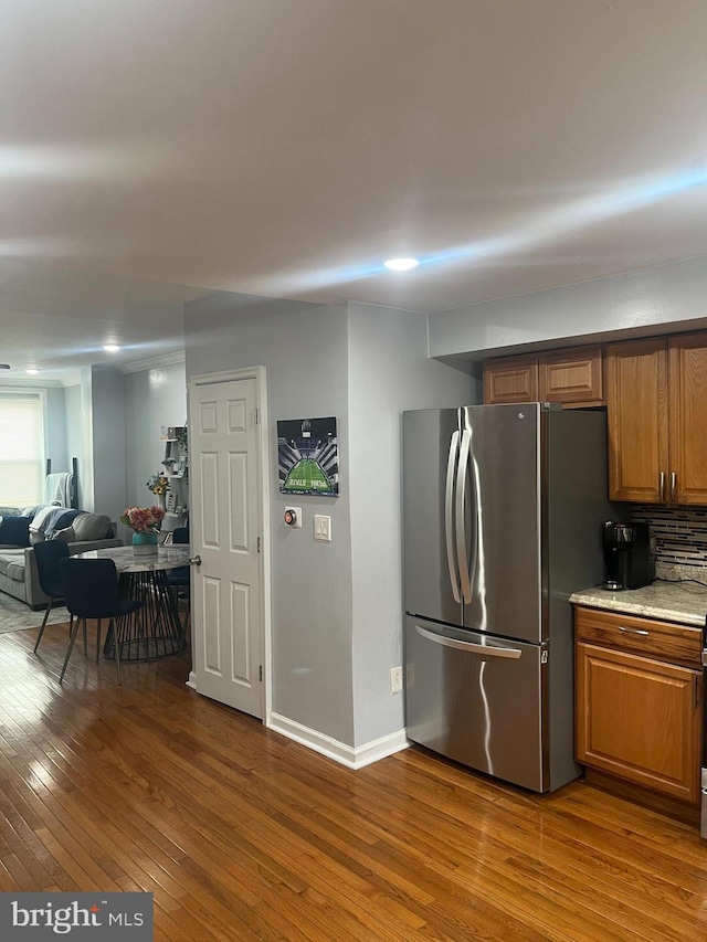 kitchen with open floor plan, freestanding refrigerator, brown cabinets, dark wood-style floors, and tasteful backsplash