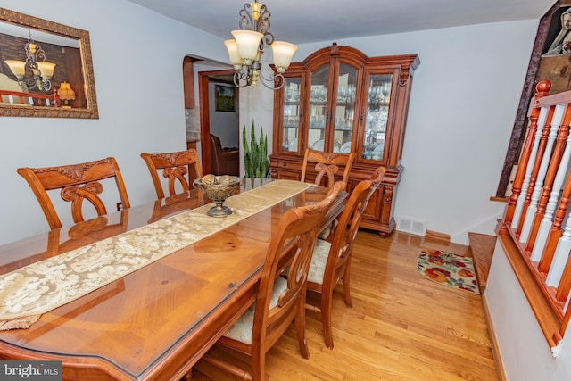 dining space featuring visible vents, baseboards, an inviting chandelier, and light wood-style flooring