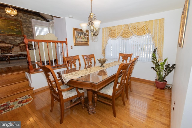 dining area featuring light wood finished floors, plenty of natural light, baseboards, and an inviting chandelier