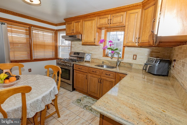 kitchen featuring under cabinet range hood, stainless steel range with gas stovetop, plenty of natural light, and a sink