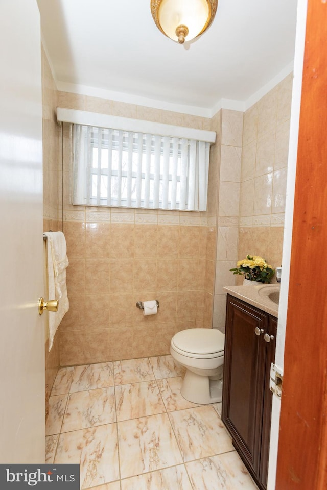 bathroom featuring toilet, vanity, tile walls, and marble finish floor