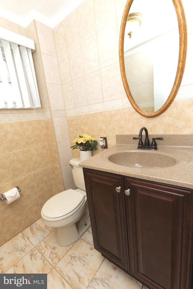 bathroom featuring marble finish floor, toilet, tile walls, and vanity