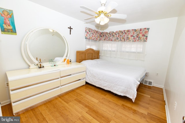 bedroom with visible vents, baseboards, wood finished floors, and a ceiling fan