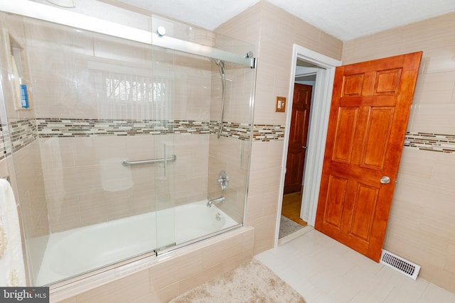 full bath with tile patterned flooring, tile walls, tiled shower / bath, and visible vents