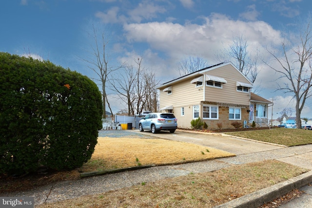 view of front of home featuring brick siding, a front lawn, and driveway