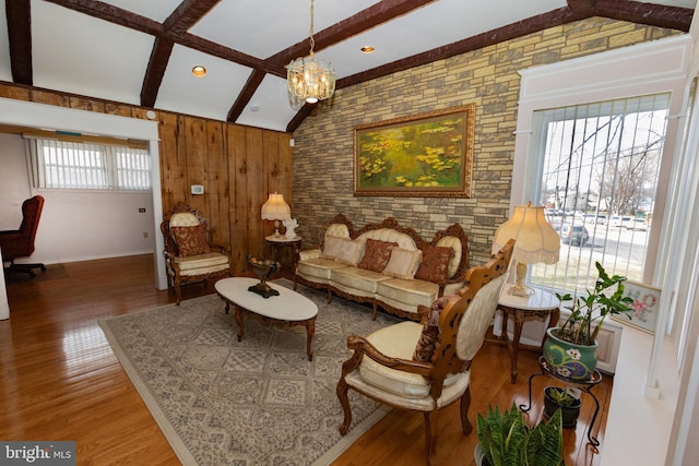 living room with an inviting chandelier, vaulted ceiling with beams, and wood finished floors