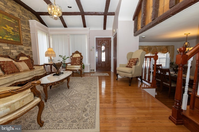 foyer entrance featuring vaulted ceiling with beams, stairs, an inviting chandelier, and hardwood / wood-style flooring