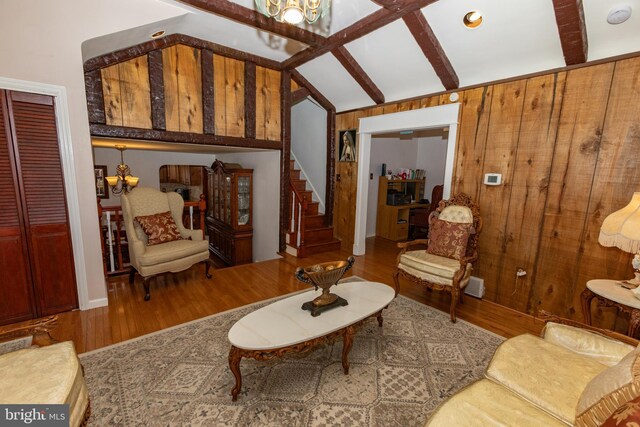 living room with an inviting chandelier, stairway, vaulted ceiling with beams, and wood finished floors