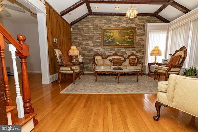 sitting room with visible vents, light wood-style flooring, a ceiling fan, stairway, and vaulted ceiling with beams