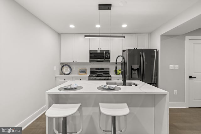 kitchen with stainless steel appliances, a center island with sink, and white cabinetry