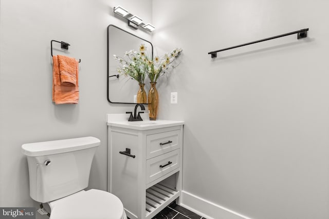 half bathroom with baseboards, vanity, and toilet