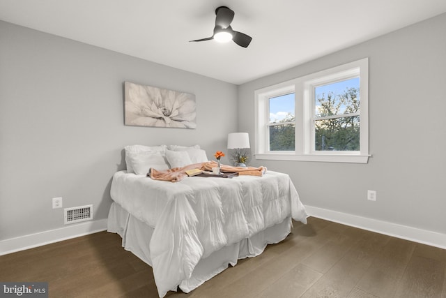 bedroom featuring dark wood-style floors, visible vents, baseboards, and a ceiling fan