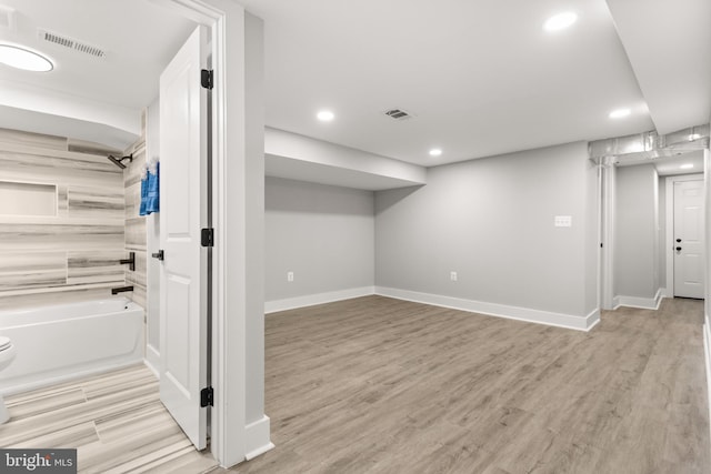 finished basement with light wood-style floors, baseboards, and visible vents