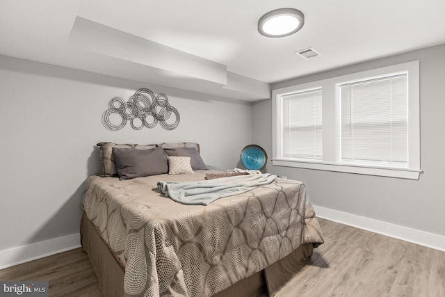 bedroom featuring visible vents, baseboards, and wood finished floors