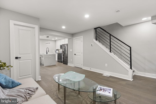 living room with recessed lighting, wood finished floors, visible vents, baseboards, and stairs