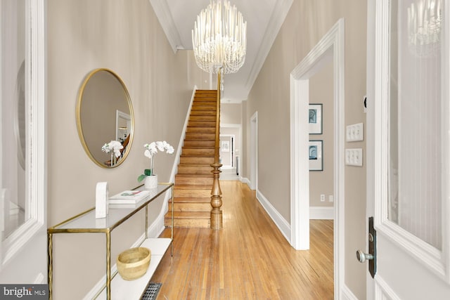 entryway featuring crown molding, light wood finished floors, visible vents, a chandelier, and stairs