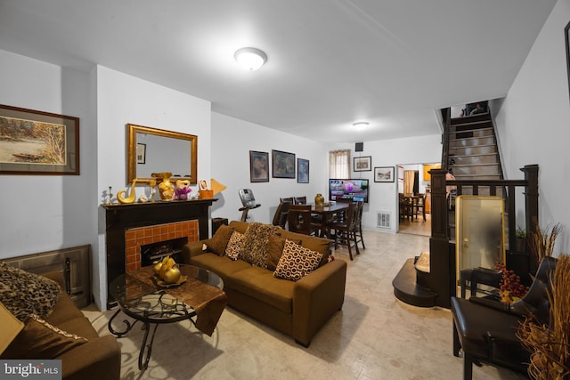 living area with stairway, a tiled fireplace, and visible vents