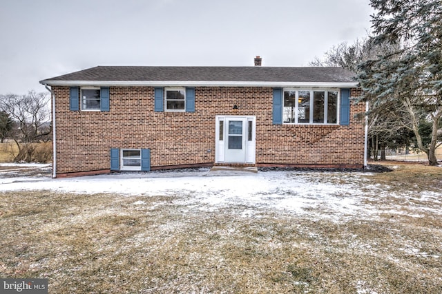 raised ranch featuring brick siding and roof with shingles