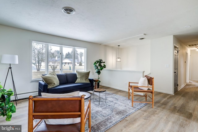 living room with baseboards, visible vents, baseboard heating, and wood finished floors