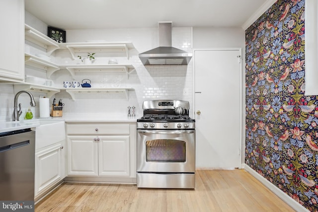 kitchen featuring wall chimney exhaust hood, appliances with stainless steel finishes, light countertops, and white cabinets