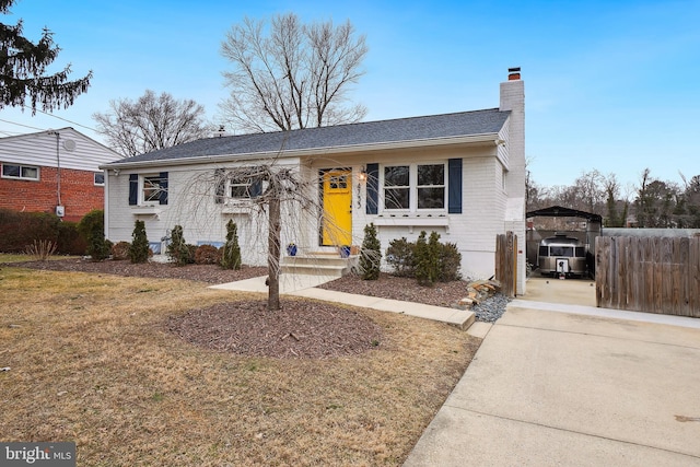 ranch-style home with entry steps, brick siding, fence, a front lawn, and a chimney